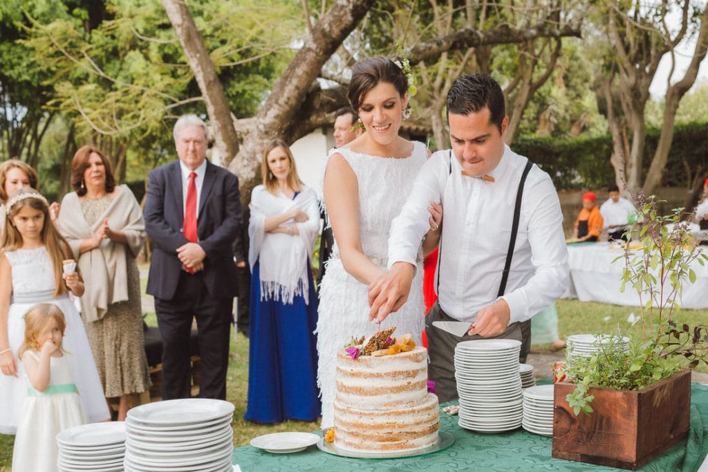 pareja de novios partiendo su pastel el dia de su boda.