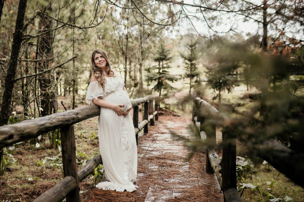 Mujer de pie entre el bosque en sus fotos de embarazo en Finca El Espinero.