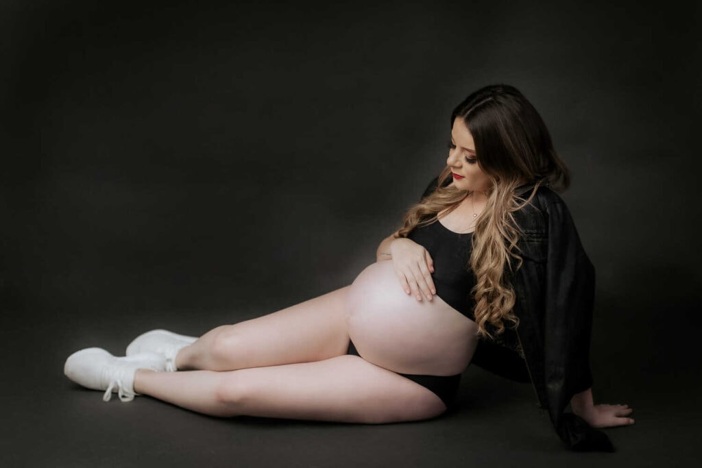 Mujer embarazada posando acostada en estudio de fotos.