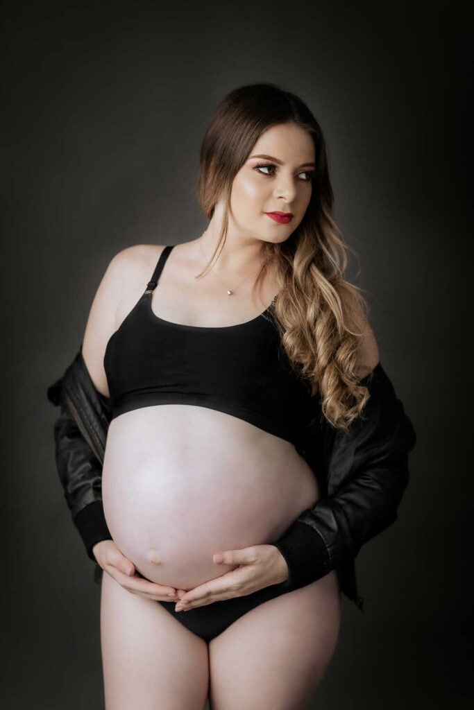 Mujer en estudio fotográfico posando en su sesión de fotografía de embarazo.