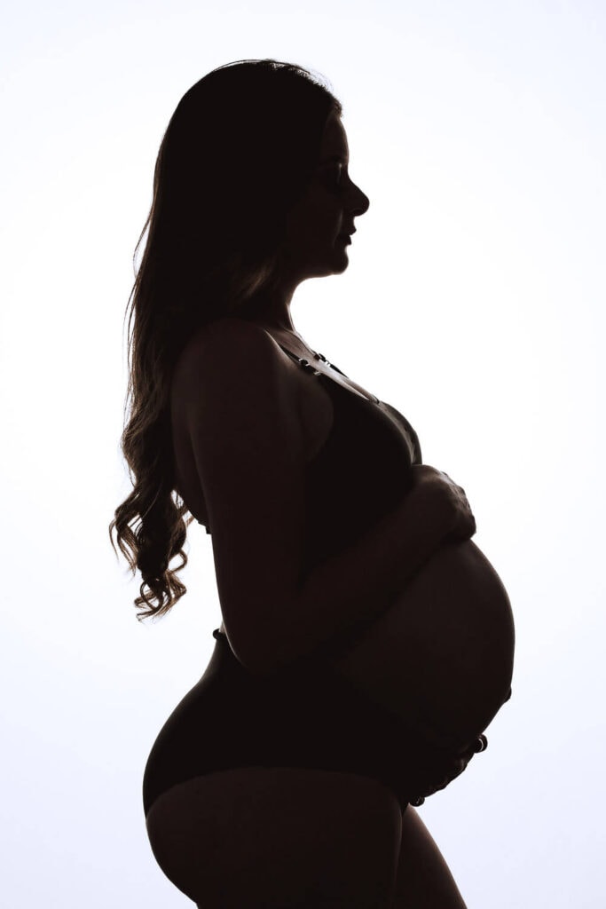 Fotografía a contra luz de embarazada en estudio.