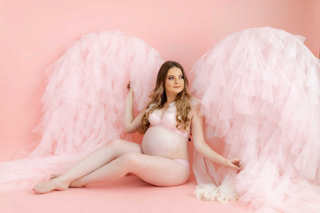 Mujer embarazada con traje de alas en sesión de fotos de embarazo.